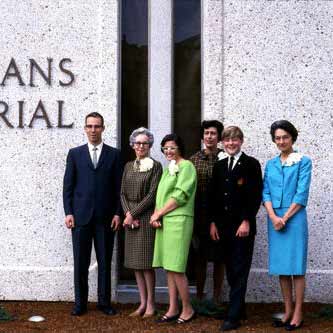 Cropped shot of well-dressed group of men and women standing in front of building from 1960s
